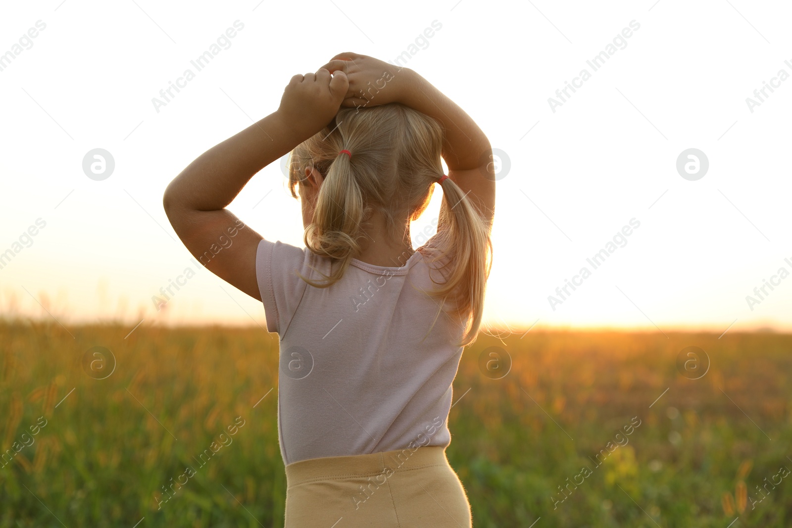 Photo of Cute little girl at meadow, back view. Child enjoying beautiful nature