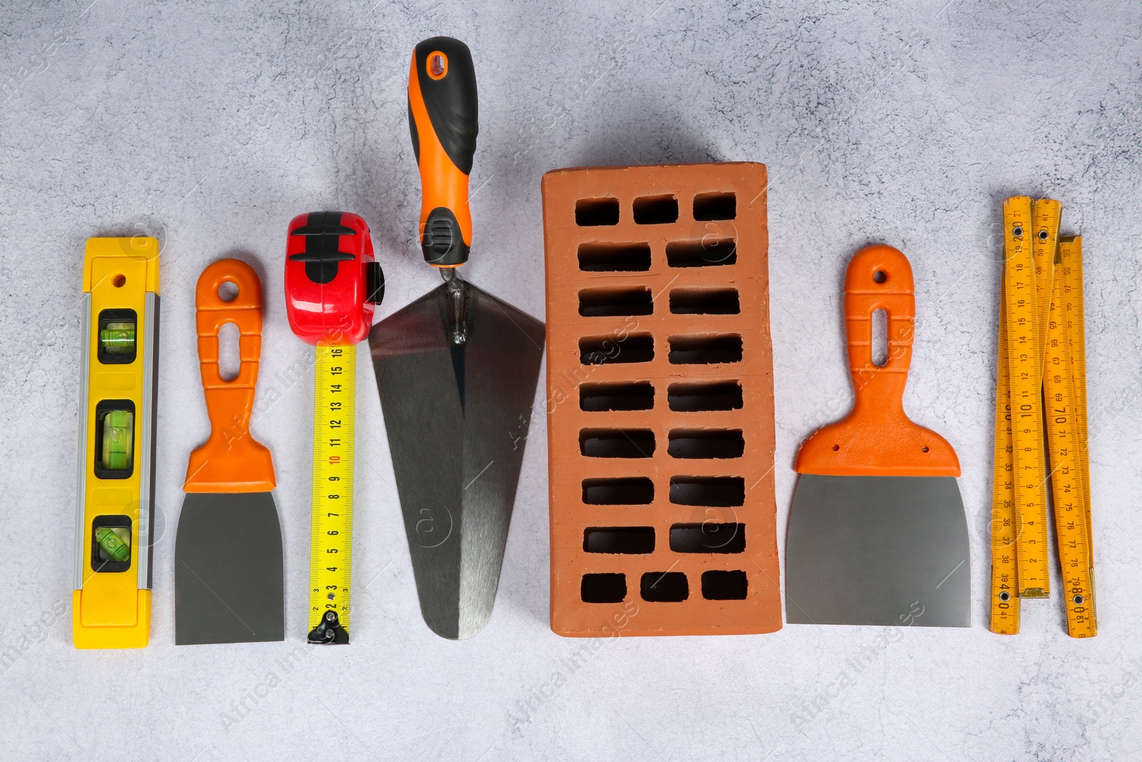 Photo of Many different construction tools and brick on light textured table, flat lay