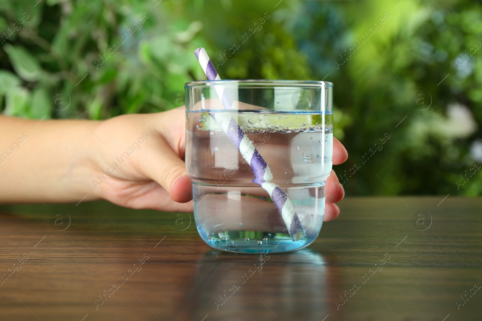 Photo of Woman with glass of soda water at wooden table, closeup