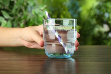 Photo of Woman with glass of soda water at wooden table, closeup