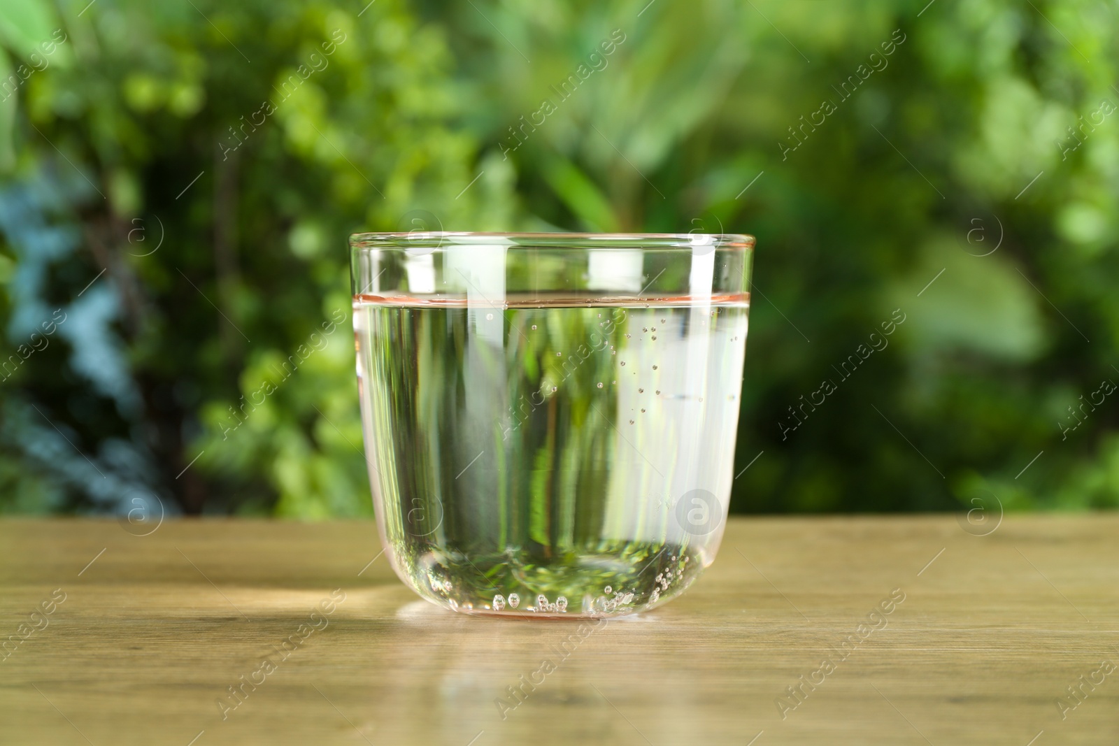 Photo of Glass of soda water on wooden table against blurred background