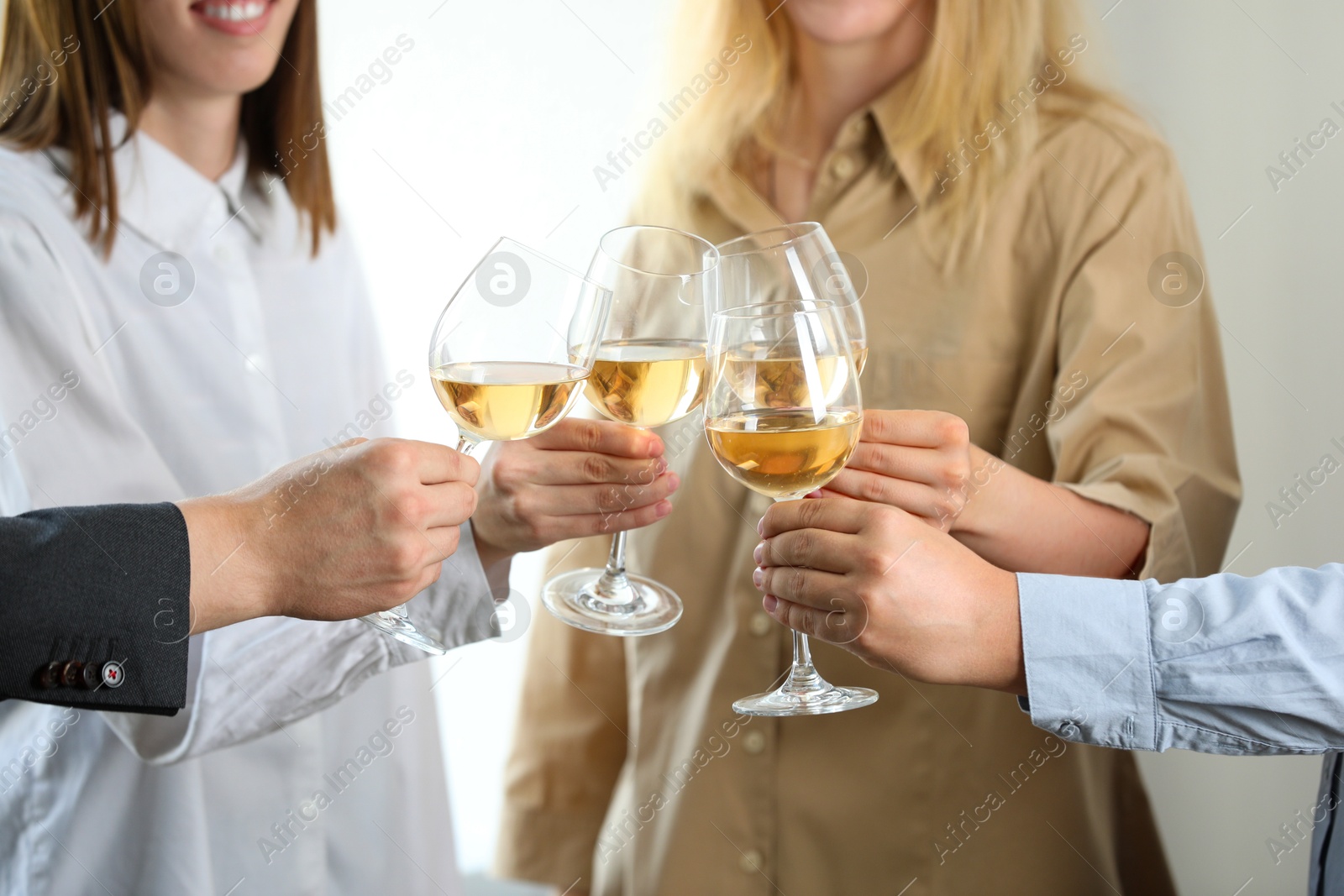 Photo of People clinking glasses of wine indoors, closeup