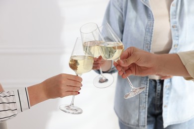 Photo of People clinking glasses of wine indoors, closeup