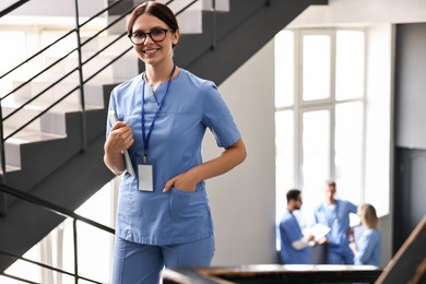 Smiling healthcare worker with tablet in hospital