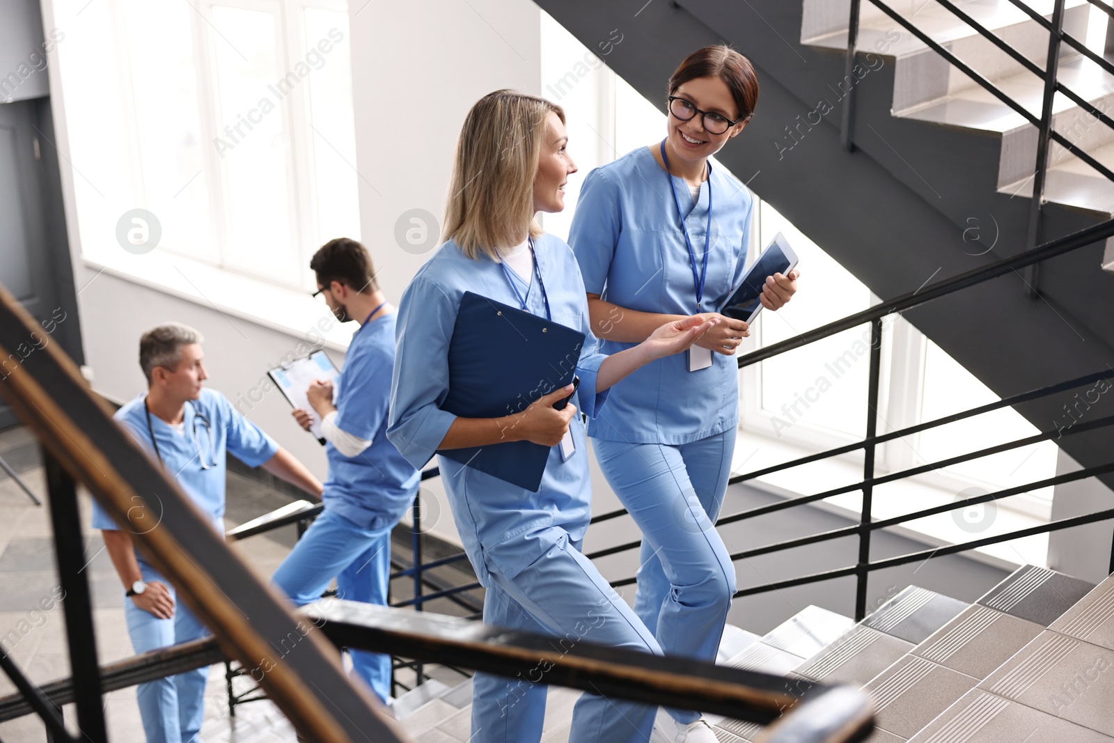 Photo of Healthcare workers with tablet and clipboard walking up stairs in hospital