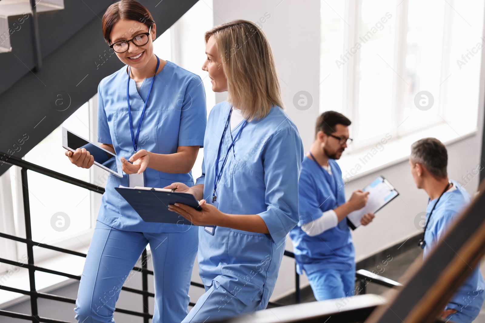 Photo of Healthcare workers with tablet and clipboard walking up stairs in hospital