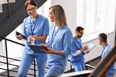 Healthcare workers with tablet and clipboard walking up stairs in hospital