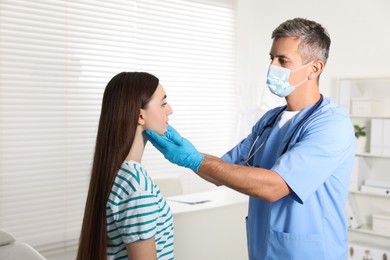 Doctor examining woman's throat in clinic during appointment