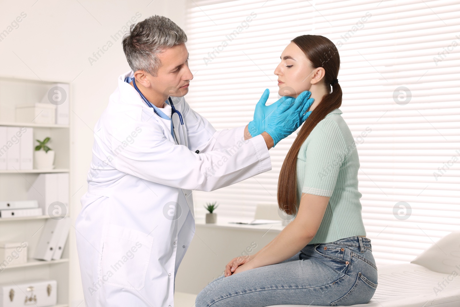 Photo of Doctor examining woman's throat in clinic during appointment