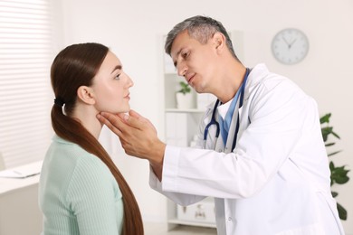 Doctor examining woman's throat in clinic during appointment