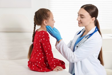 Photo of Doctor examining girl's throat in clinic during appointment