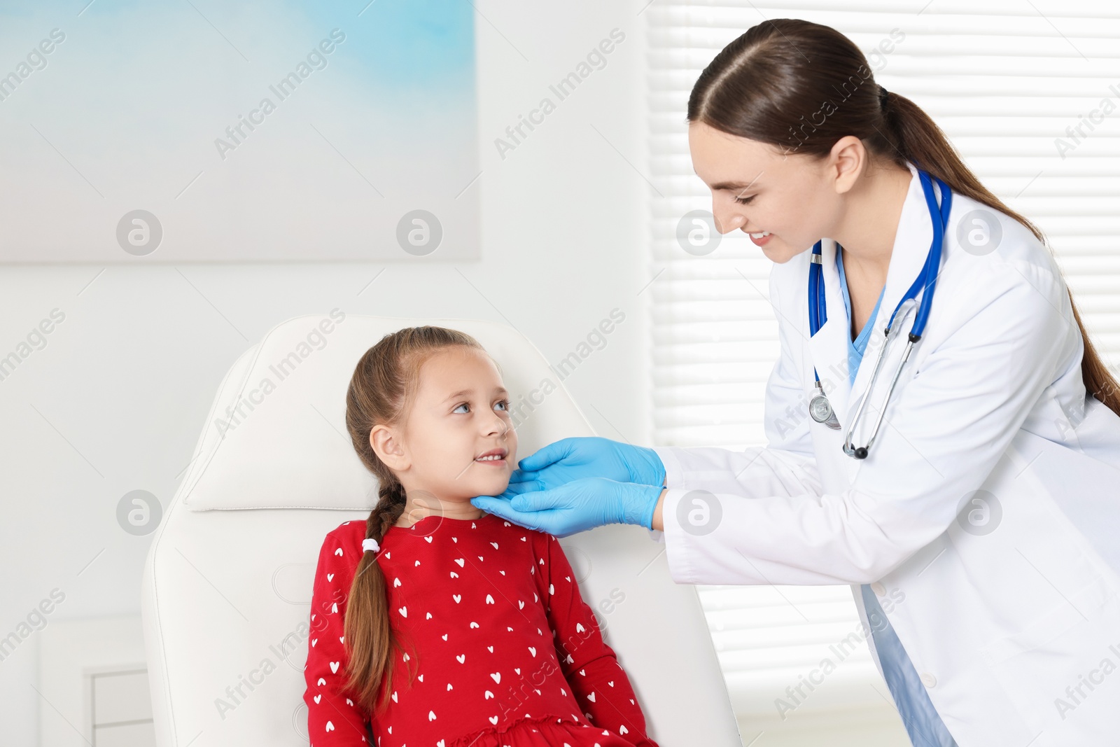 Photo of Doctor examining girl's throat in clinic during appointment