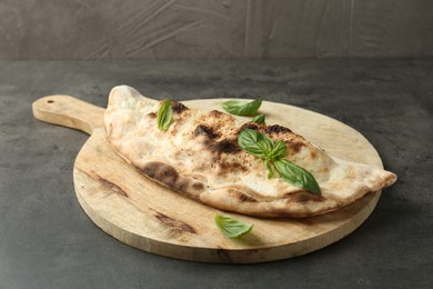 Delicious calzone with fresh basil on grey textured table