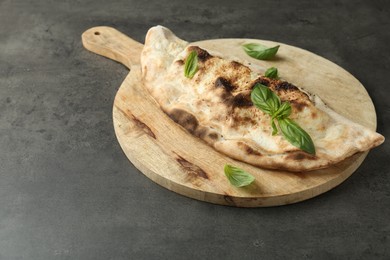 Delicious calzone with fresh basil on grey textured table