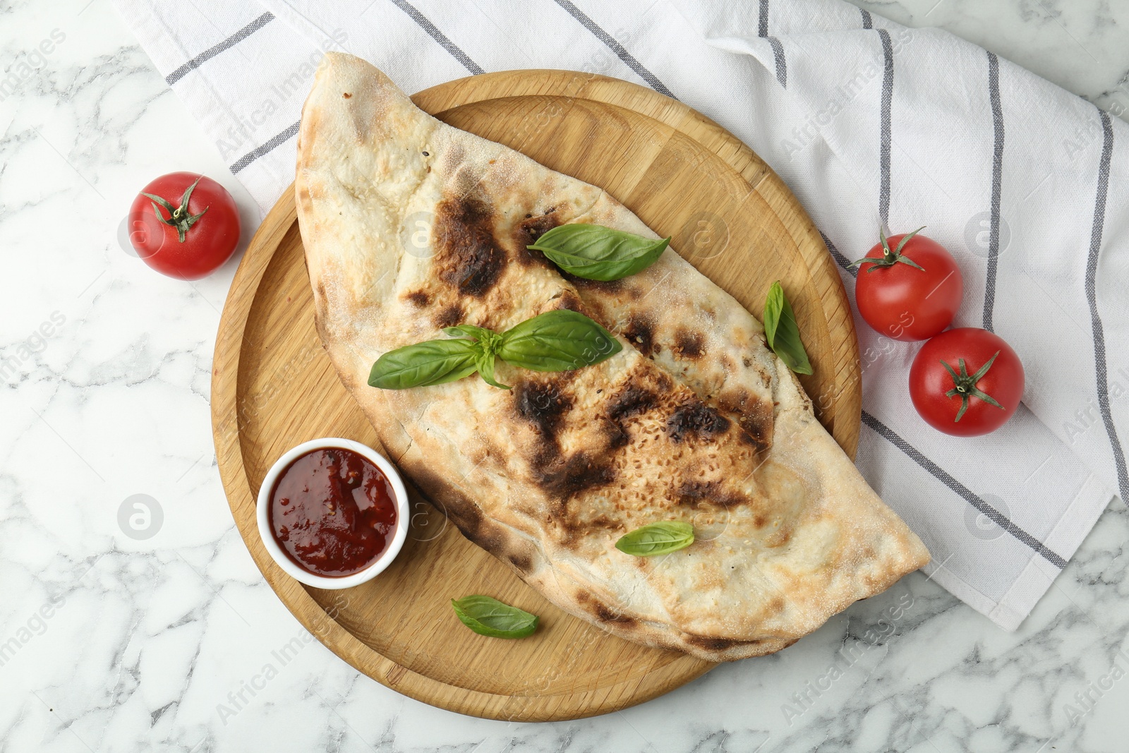 Photo of Delicious calzone served on white marble table, top view