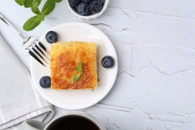 Photo of Slice of tasty semolina cake served on white textured table, flat lay. Space for text