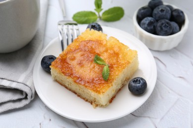 Photo of Slice of tasty semolina cake served on white textured table, closeup