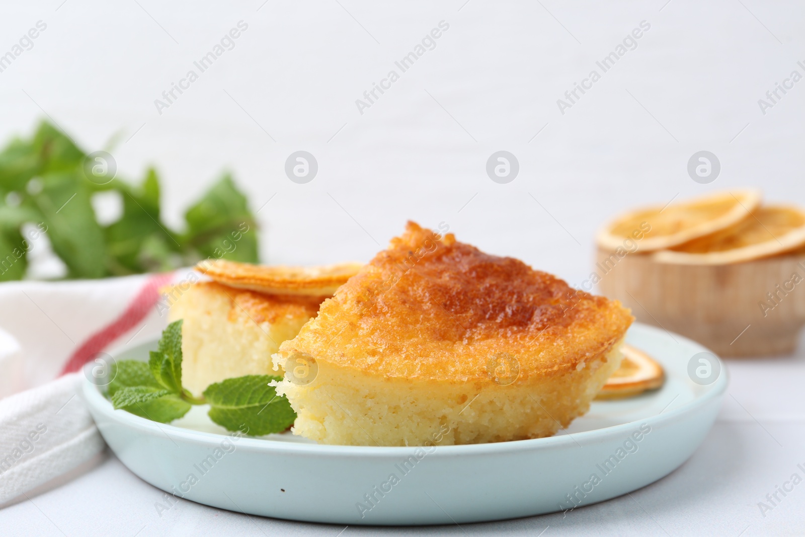 Photo of Tasty semolina cake served on white tiled table, closeup