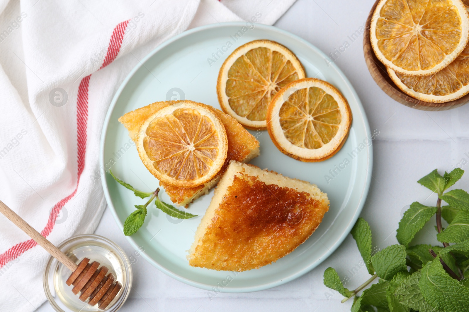 Photo of Tasty semolina cake served on white tiled table, flat lay