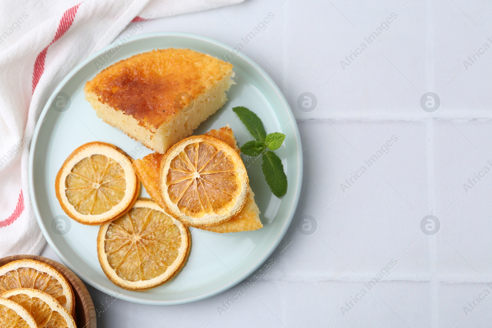 Photo of Tasty semolina cake served on white tiled table, flat lay. Space for text