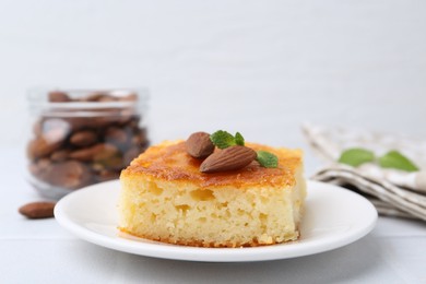 Photo of Slice of tasty semolina cake served on white tiled table, closeup