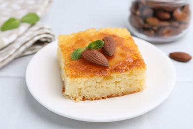 Photo of Slice of tasty semolina cake served on white tiled table, closeup