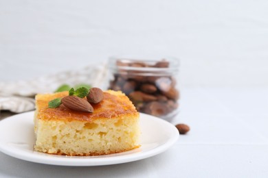 Photo of Slice of tasty semolina cake served on white tiled table, closeup. Space for text