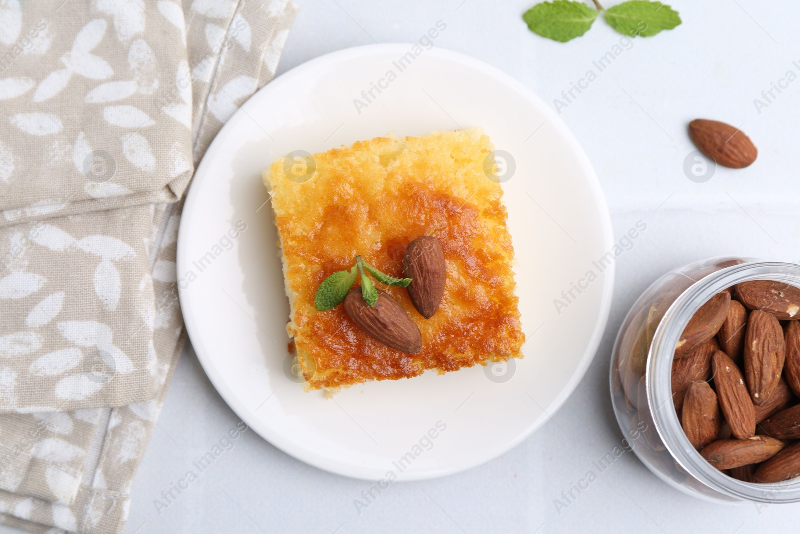 Photo of Slice of tasty semolina cake served on white tiled table, flat lay