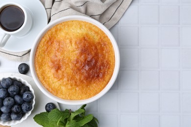 Photo of Tasty semolina cake served on white tiled table, flat lay. Space for text