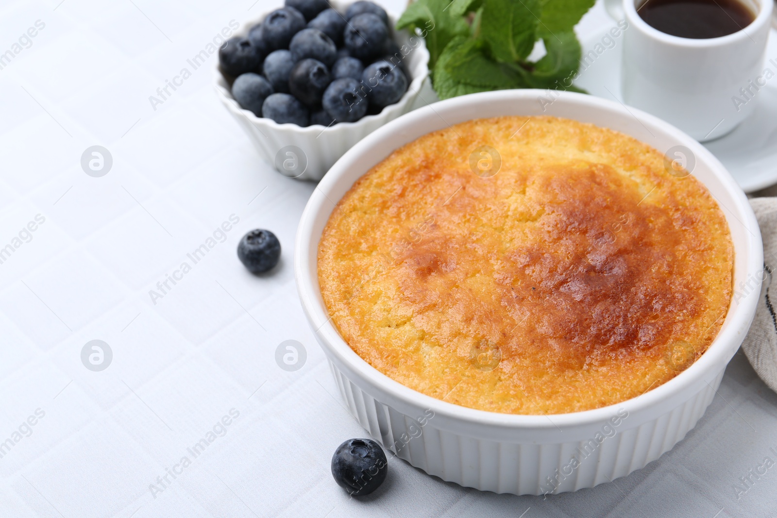 Photo of Tasty semolina cake served on white tiled table, closeup. Space for text