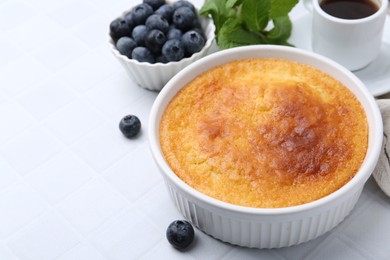 Photo of Tasty semolina cake served on white tiled table, closeup. Space for text