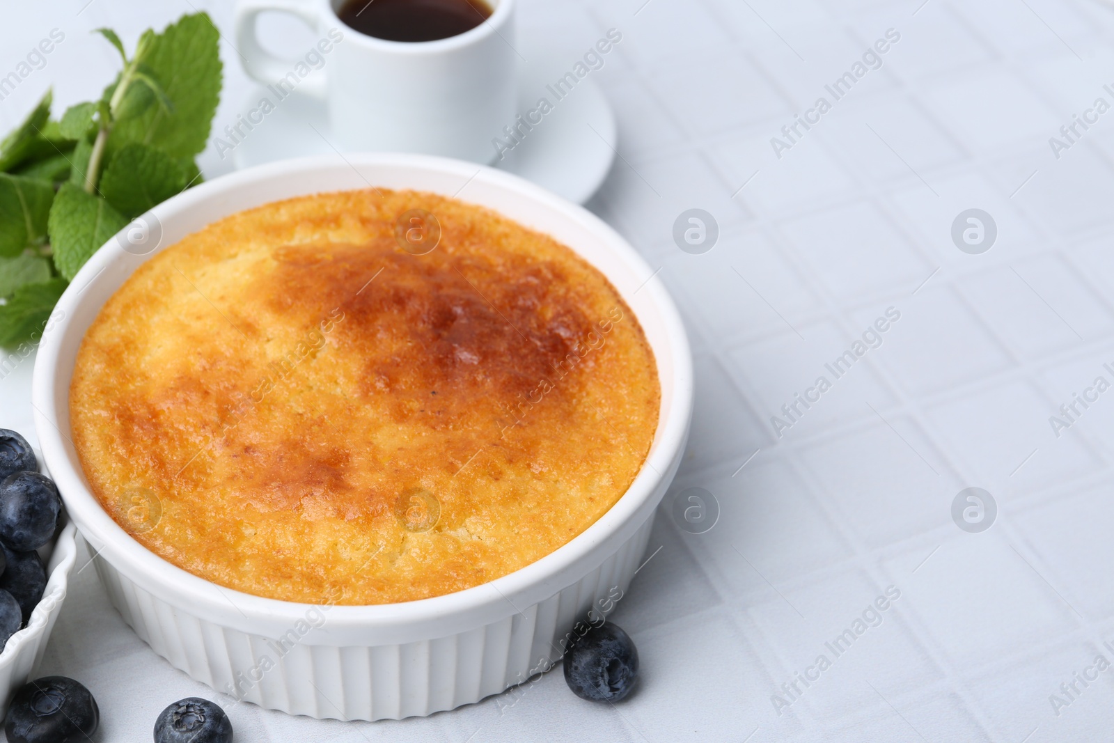 Photo of Tasty semolina cake served on white tiled table, closeup. Space for text