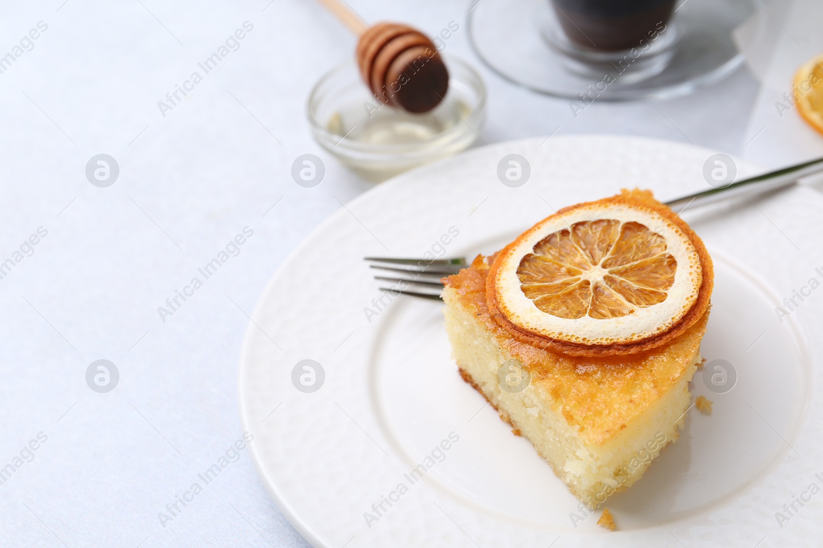 Photo of Slice of tasty semolina cake served on white table, closeup. Space for text