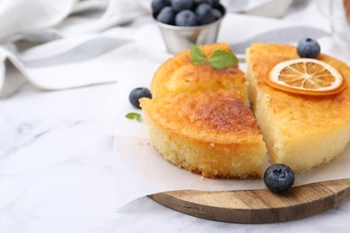 Photo of Tasty semolina cake served on white marble table, closeup. Space for text