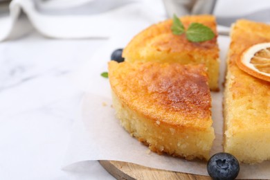 Photo of Tasty semolina cake served on white marble table, closeup. Space for text