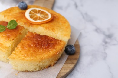 Photo of Tasty semolina cake served on white marble table, closeup. Space for text