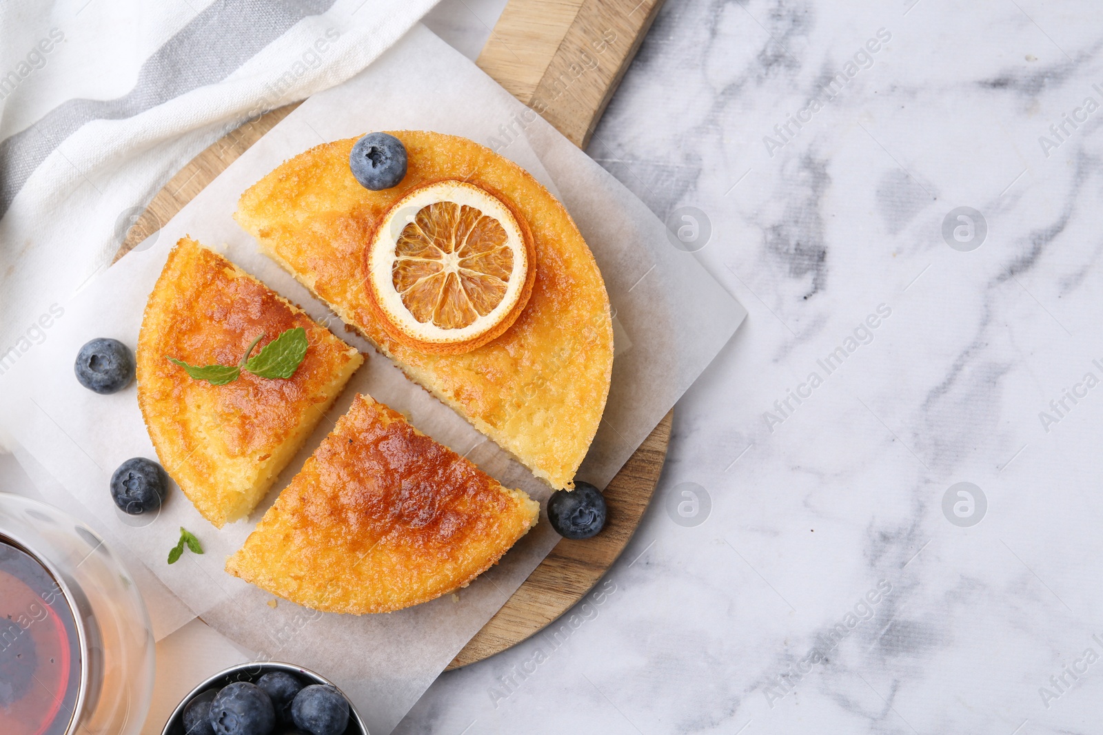 Photo of Tasty semolina cake served on white marble table, flat lay. Space for text