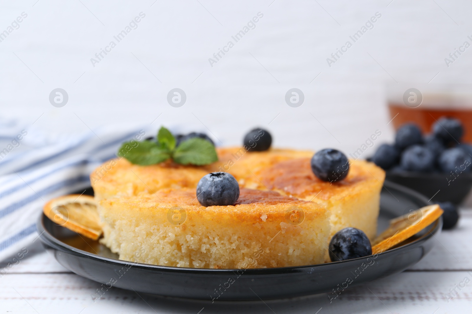 Photo of Delicious semolina cake with blueberries and orange slices on white wooden table, closeup