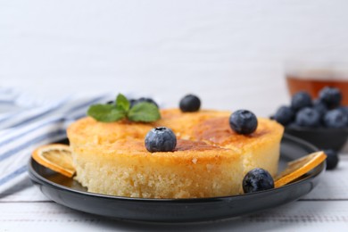 Photo of Delicious semolina cake with blueberries and orange slices on white wooden table, closeup