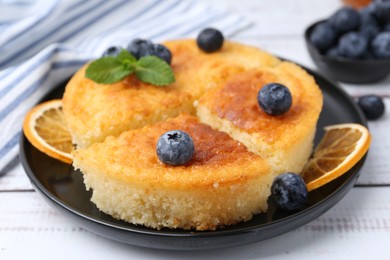 Photo of Delicious semolina cake with blueberries and orange slices on white wooden table, closeup