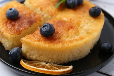 Photo of Delicious semolina cake with blueberries and orange slices on white wooden table, closeup