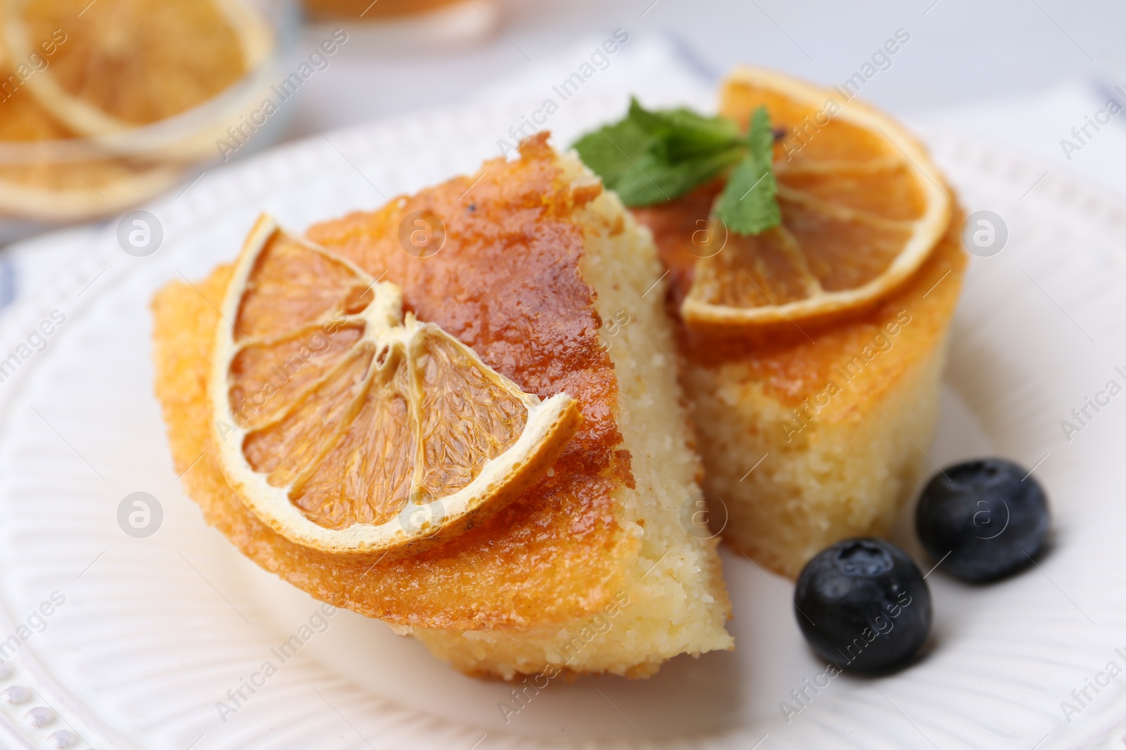 Photo of Pieces of delicious semolina cake with blueberries and orange slices on table, closeup