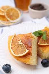 Photo of Pieces of delicious semolina cake with blueberries and orange slices on table, closeup