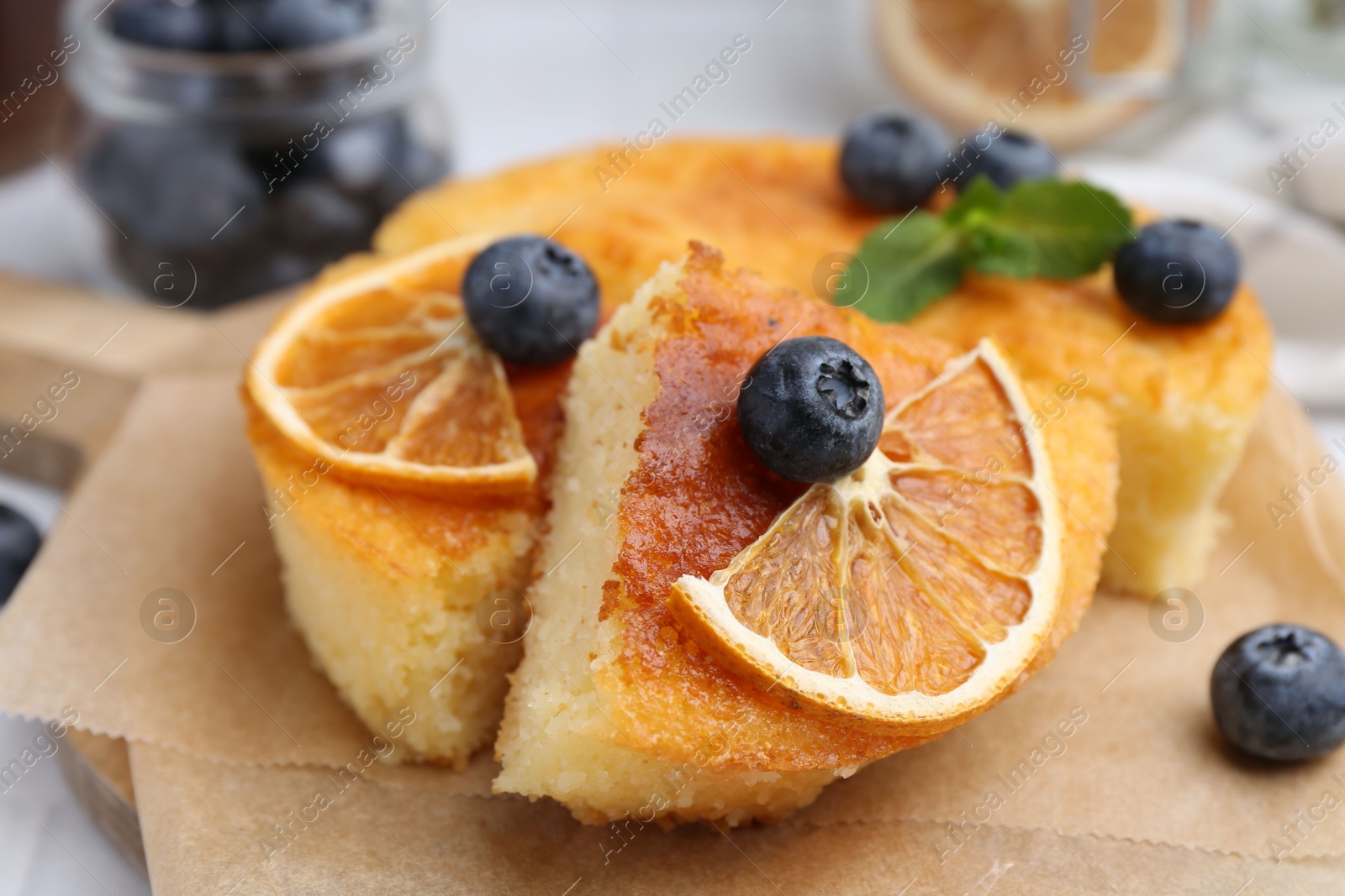 Photo of Pieces of delicious semolina cake with blueberries and orange slices on table, closeup