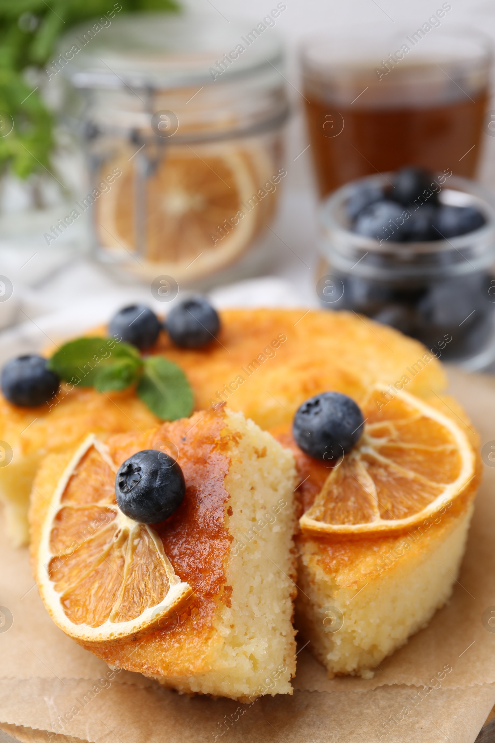 Photo of Pieces of delicious semolina cake with blueberries and orange slices on table, closeup