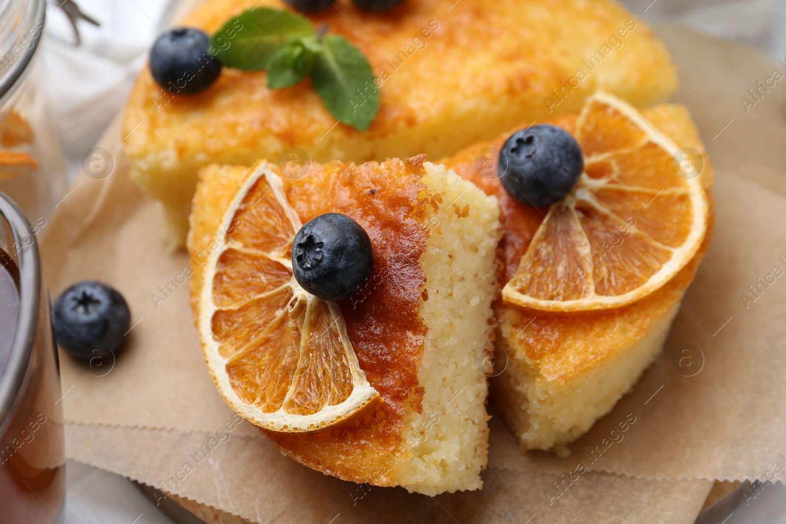 Photo of Pieces of delicious semolina cake with blueberries and orange slices on table, closeup