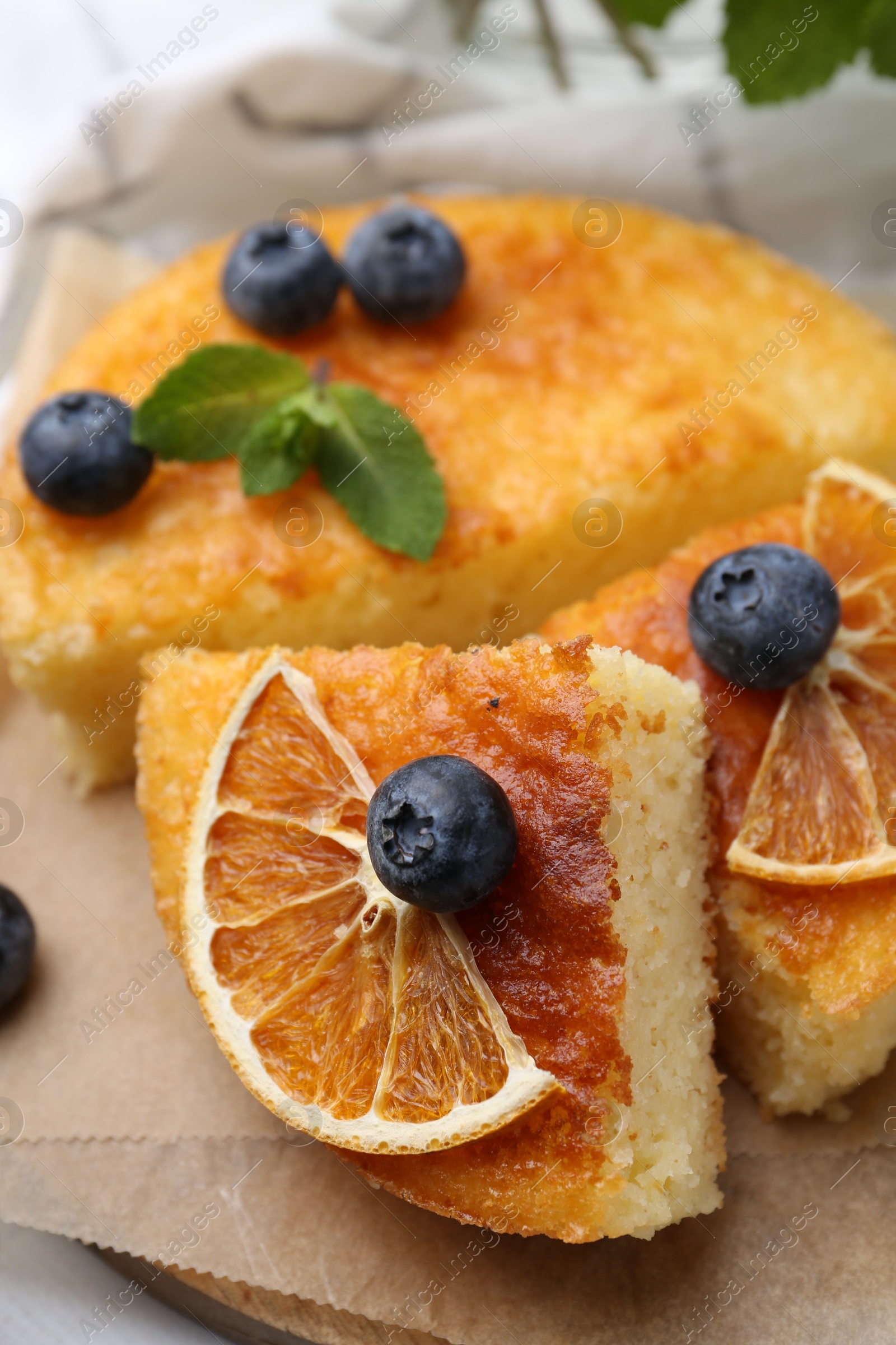 Photo of Pieces of delicious semolina cake with blueberries and orange slices on table, closeup