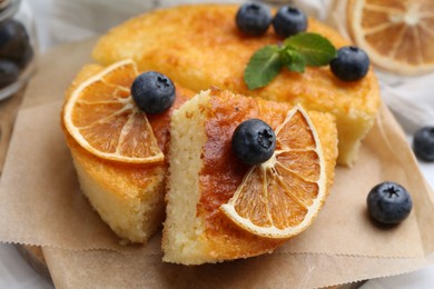 Photo of Pieces of delicious semolina cake with blueberries and orange slices on table, closeup