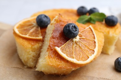 Photo of Pieces of delicious semolina cake with blueberries and orange slices on table, closeup