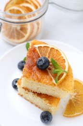 Photo of Pieces of delicious semolina cake with blueberries and orange slices on table, closeup